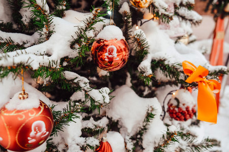Christmas tree adorned with colorful ornaments and snow-covered branches for festive ambianceの写真素材
