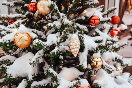 Snow-covered Christmas tree adorned with colorful ornaments and festive decorationsの写真素材