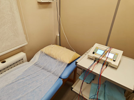Physical therapy treatment room featuring a blue examination bed with a pillow, medical equipment on...