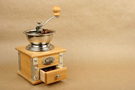 coffee mill full of beans on brown background