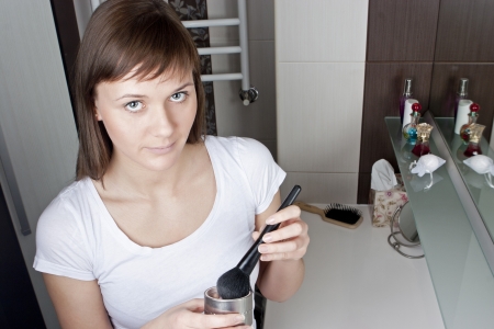 Attractive young woman applying make-up in her bathroomの写真素材
