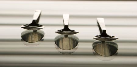 The three silver spoons with reflection in a mirrorの写真素材