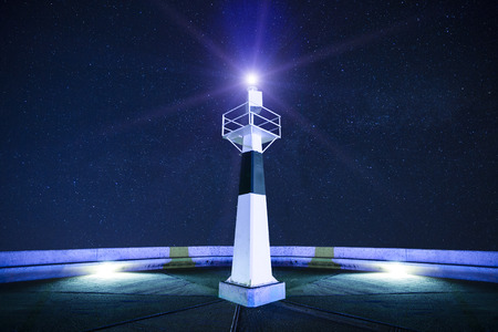 Lighthouse at starry night with searchlight beamの写真素材
