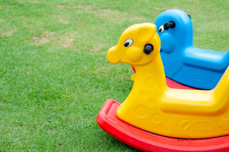 Colorful plastic rocking horse in the backyard. Lay on green grass background.の写真素材