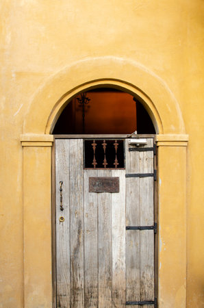 Vintage wooden door on the yellow pastel wall backgroundの写真素材