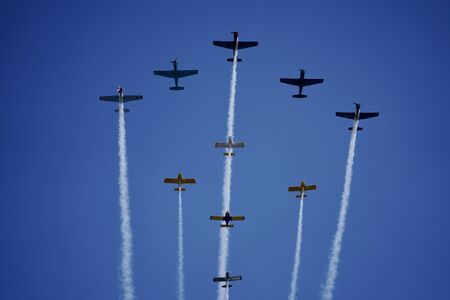 Planes fly overhead in formation leaving contrails on a blue sky.の写真素材
