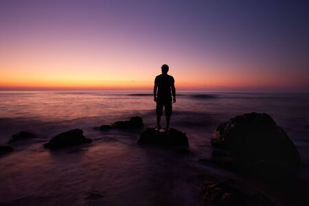 Man wach colorful sunrise from rocks near the beach; Bulgarian Black sea beautiful morning;の写真素材