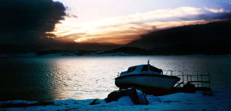 dramatic sunrise over lake with boat on the beach