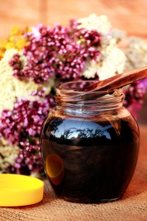cup with honey and several colorful herbs in background の写真素材