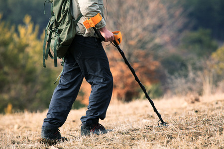man hunt treasure with metal detector in autumn forest の写真素材