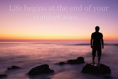 man on the edge on rock in calm sea sunrise, unknown inspirational quote aboveの写真素材