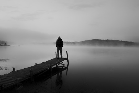 black and white abstract landscape with man stand on wooden bridge in sunrise lake の写真素材