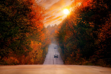 colorful HDR red sunset over the straight high mountain autumn roadの写真素材