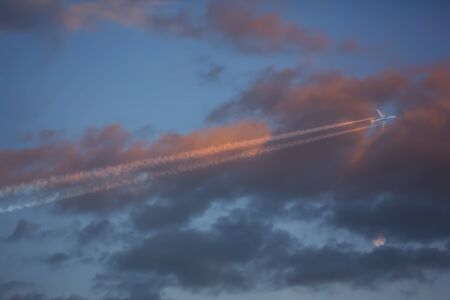 airplane flying close to the moon- red cloudy sunset