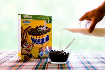 SOFIA , BULGAIRA  April 29, 2015: box Nesquick morning cereal and human hand with milk. Nesquick is made by Nestle the largest food company in the world measured by revenues and was founded in 1905のeditorial素材