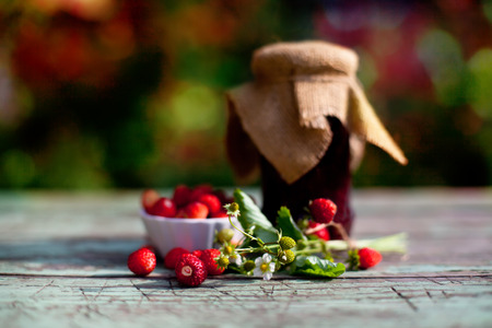 wild strawberry jam on wooden table, soft red and green bokeh backgrondの写真素材