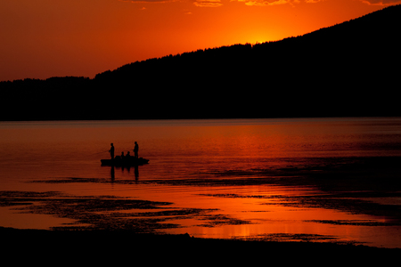 Red sunset and fishing boat silhouette, high mountain bulgarian Batak dam lakeの写真素材