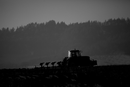 black and white agricultural farmland landscape with silhouette ot trator の写真素材