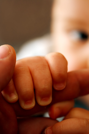 young baby holding older hand- focus on child handの写真素材