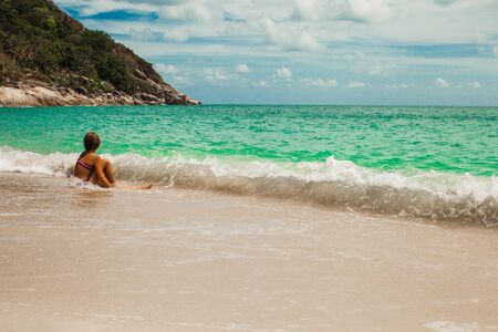 little beautiful girl summer sitting on a rock by the sea and playing pan pipeの写真素材