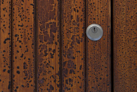 detail of keyhole on old wooden door with peeling paint textureの写真素材