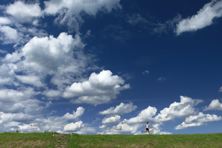 beautiful blue sky with small unidentifiable running healthy human figureの写真素材