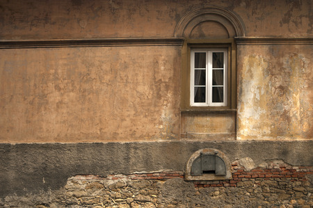 windows with arch relief on forgotten empty wall painted with many layers of fading warm tonesの写真素材