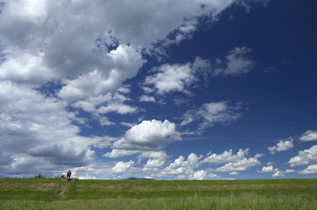 tiny insignificant red human figure contrasting vast cloudy blue sky expanseの写真素材