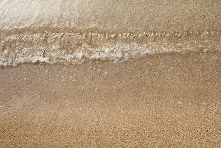 small wave on surface of golden sandy beach