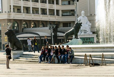 Group of students sitting next to the fountain posing in front of their friends camera,in the square in the center of Skopje city のeditorial素材
