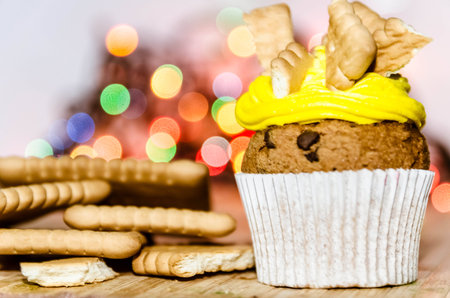 Yellow cream cupcake with bisquits on top of it 