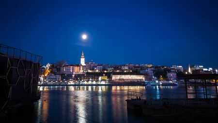 Night landscape of Belgrade from the bank of the river Sava, full moon in the sky above the city.の写真素材