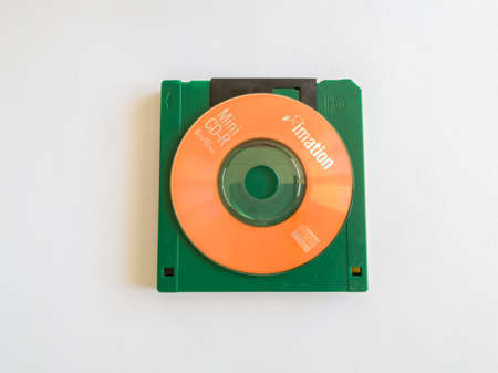 Mini CDs stacked on floppy disks, objects isolated on a white background, the evolution of technology.のeditorial素材