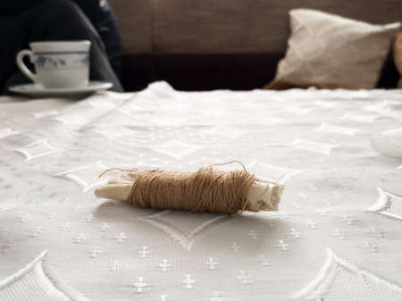Sewing thread isolated on a white tablecloth in the living room.