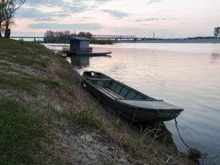 Picturesque view of the Sava River in Bosanski Brod with moored fishing boats along the shore during a cloudy evening.の写真素材
