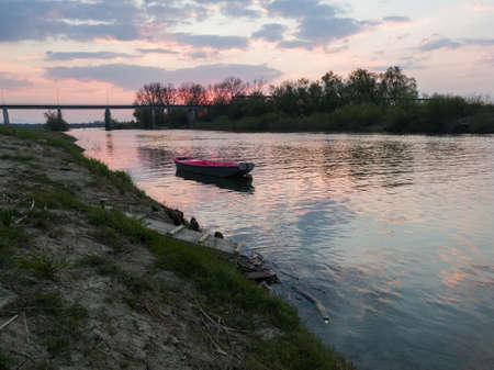 Picturesque view of the Sava River in Bosanski Brod with a broken dock, a boat in the water and the...