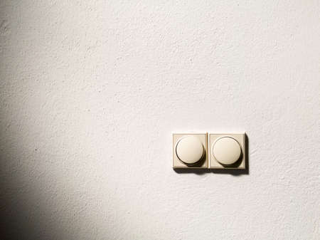 Two plastic light switches on a white painted wall in the house in daylightの写真素材
