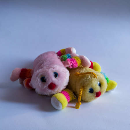 Isolated children's toy against a white background, two old torn centipedes yellow and pink from childhoodの写真素材