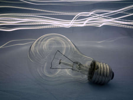 Electric light bulb on a blue texture background in the dark with light traces in the background.の写真素材
