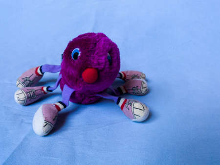Isolated children's toy against a blue texture background, teddy bear from childhood, an old purple centipedeの写真素材