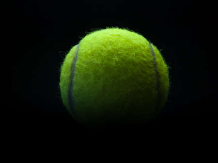 Sports props, close up of tennis ball against a dark backgroundの写真素材