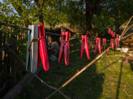 Old cracked clothes pegs hanging on a clothesline against the village yard during the eveningの写真素材