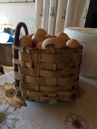 A wicker basket made of wood or sepet full of chicken eggs on the porch table during day.の写真素材