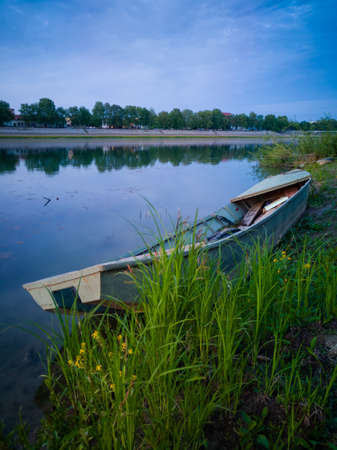 An old stranded boat in the grass on the bank of the Sava River during the blue hour in Bosanski Brod.の写真素材