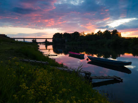 Beautiful landscape of the Sava river with reflection during sunset, Fishing boats moored to wooden...