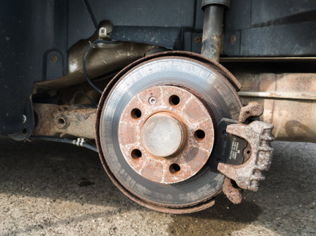 Brake disc system, pads and shield of vehicle without wheels for repair or replacement close up, suspension of car, process of new tire replacement, service concept, maintain rusty car partsのeditorial素材