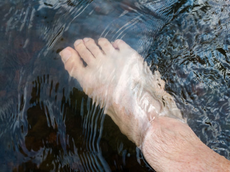 Close up human foot while stand in rapid water stream, relax in shallow creek, day off in nature, vacation or holiday conceptの写真素材