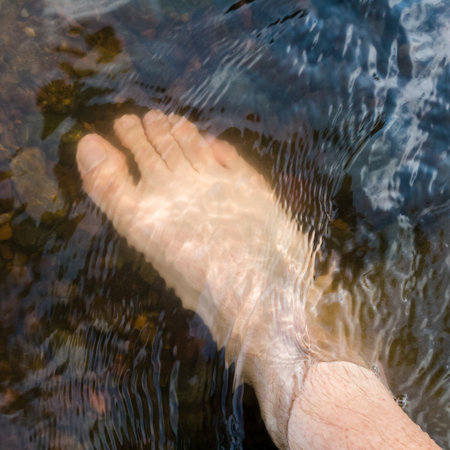 Close up human foot while stand in rapid water stream, relax in shallow creek, day off in nature, vacation or holiday conceptの写真素材