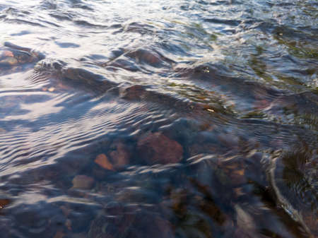Wavy rippling water surface of rapids in stream and stones at bottom, swelled creek after rain, hydro energyの写真素材