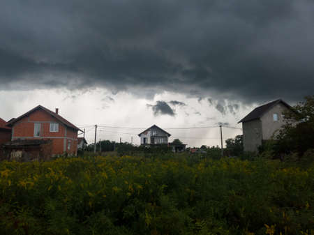 Dangerous dramatic dark clouds above settlement, ominous stormy weather with rain during summerのeditorial素材